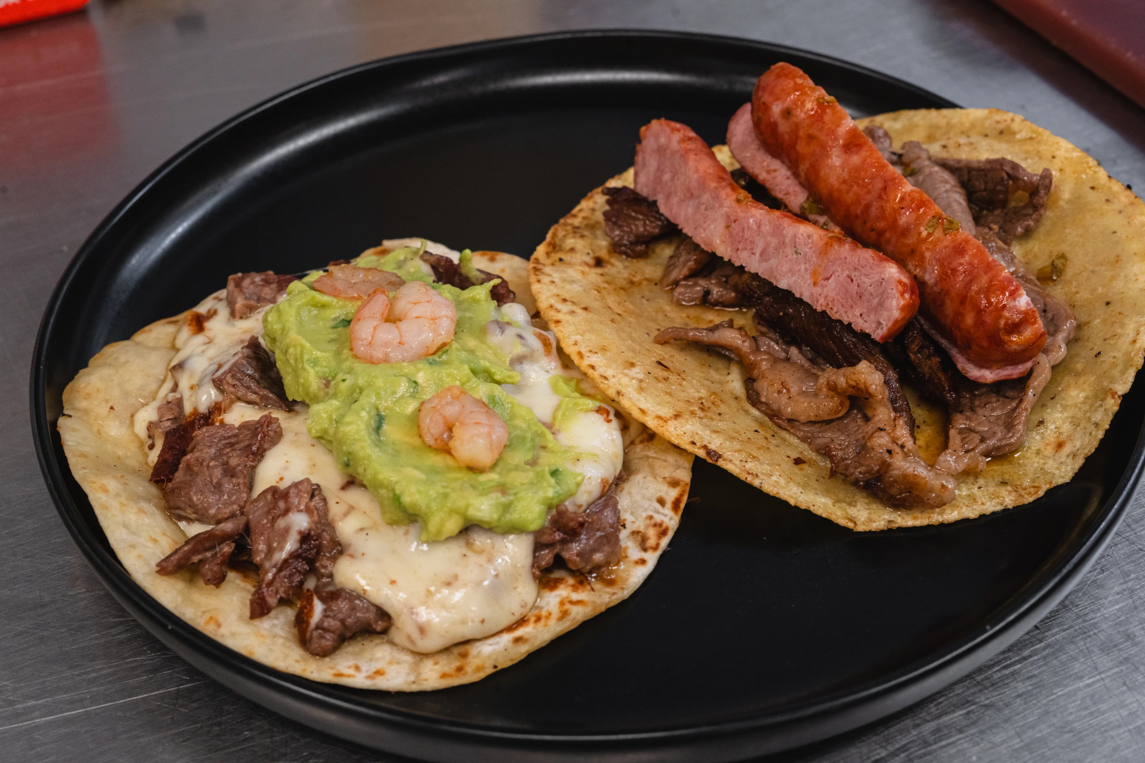 Prime-cut tacos on a black plate, fresh off the Alta Brasa brasa